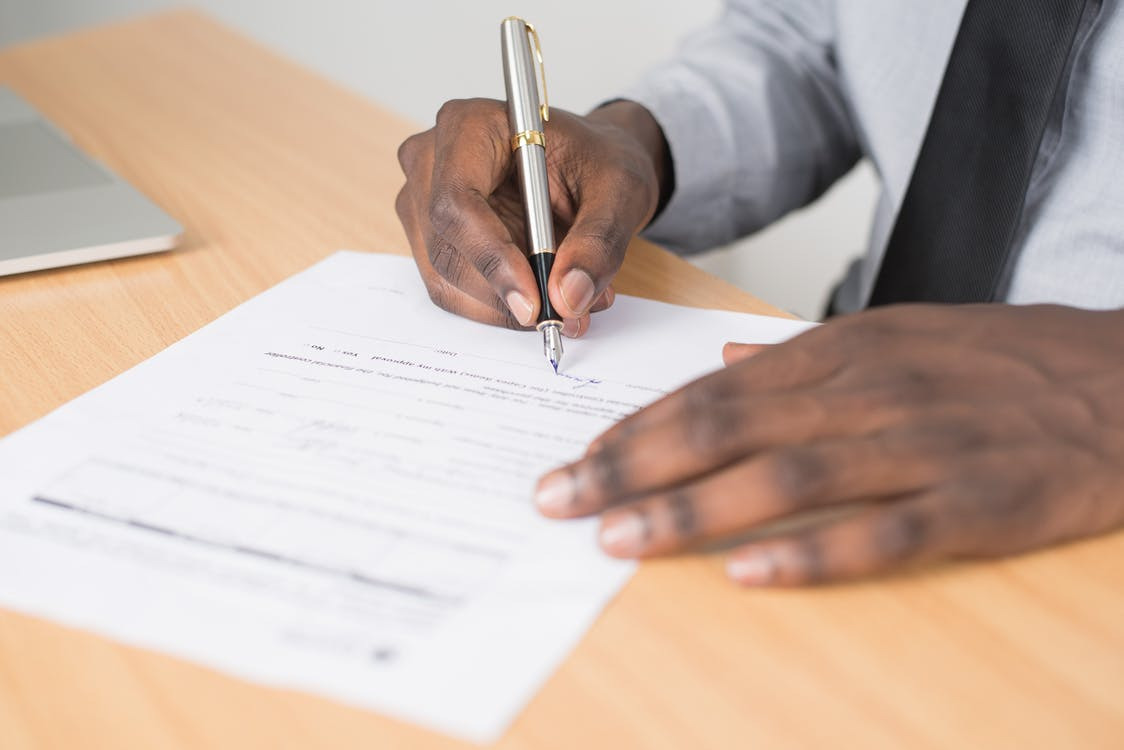 Cropped image of a person signing a paper